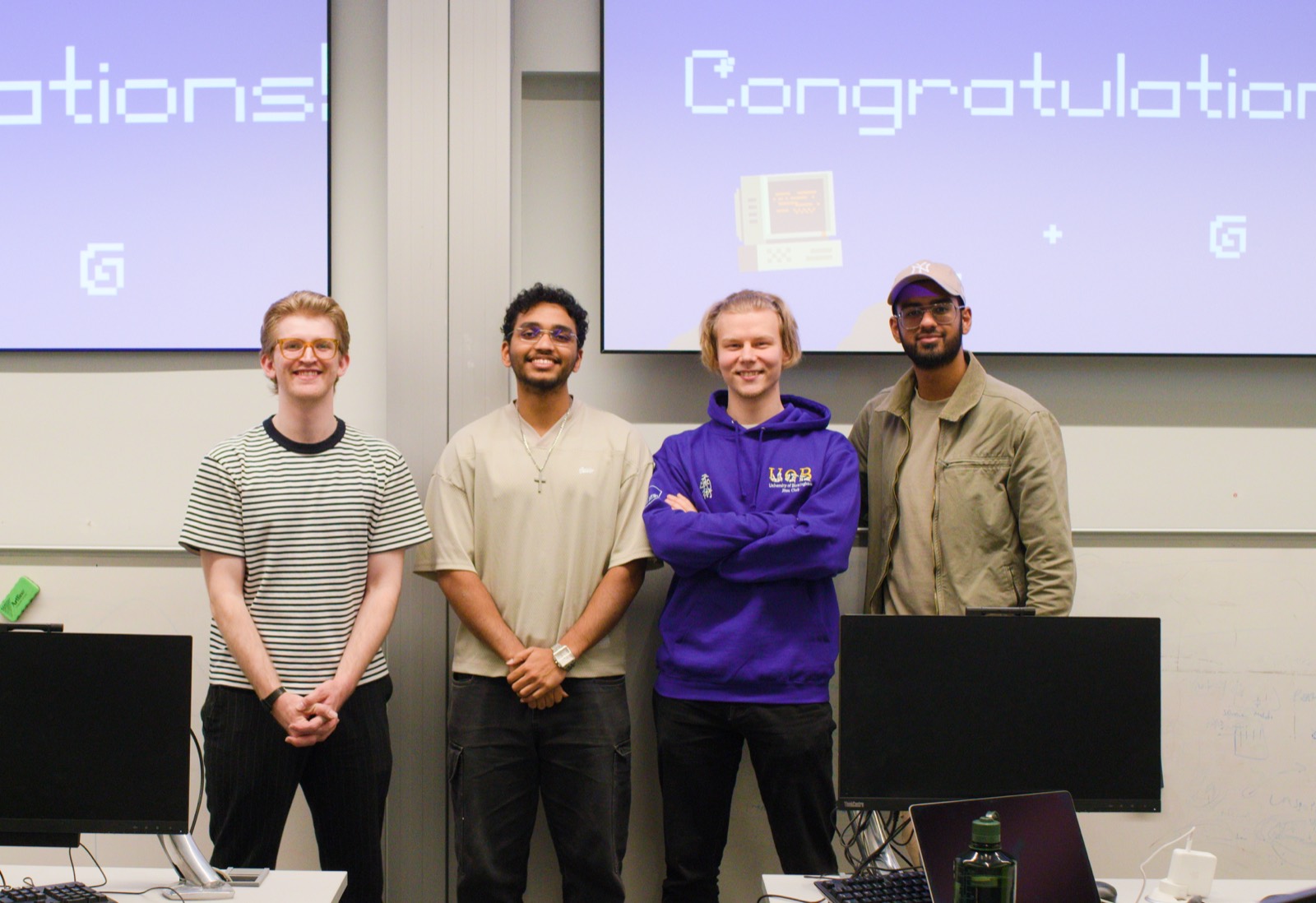Four members standing together in front of the screen after a build