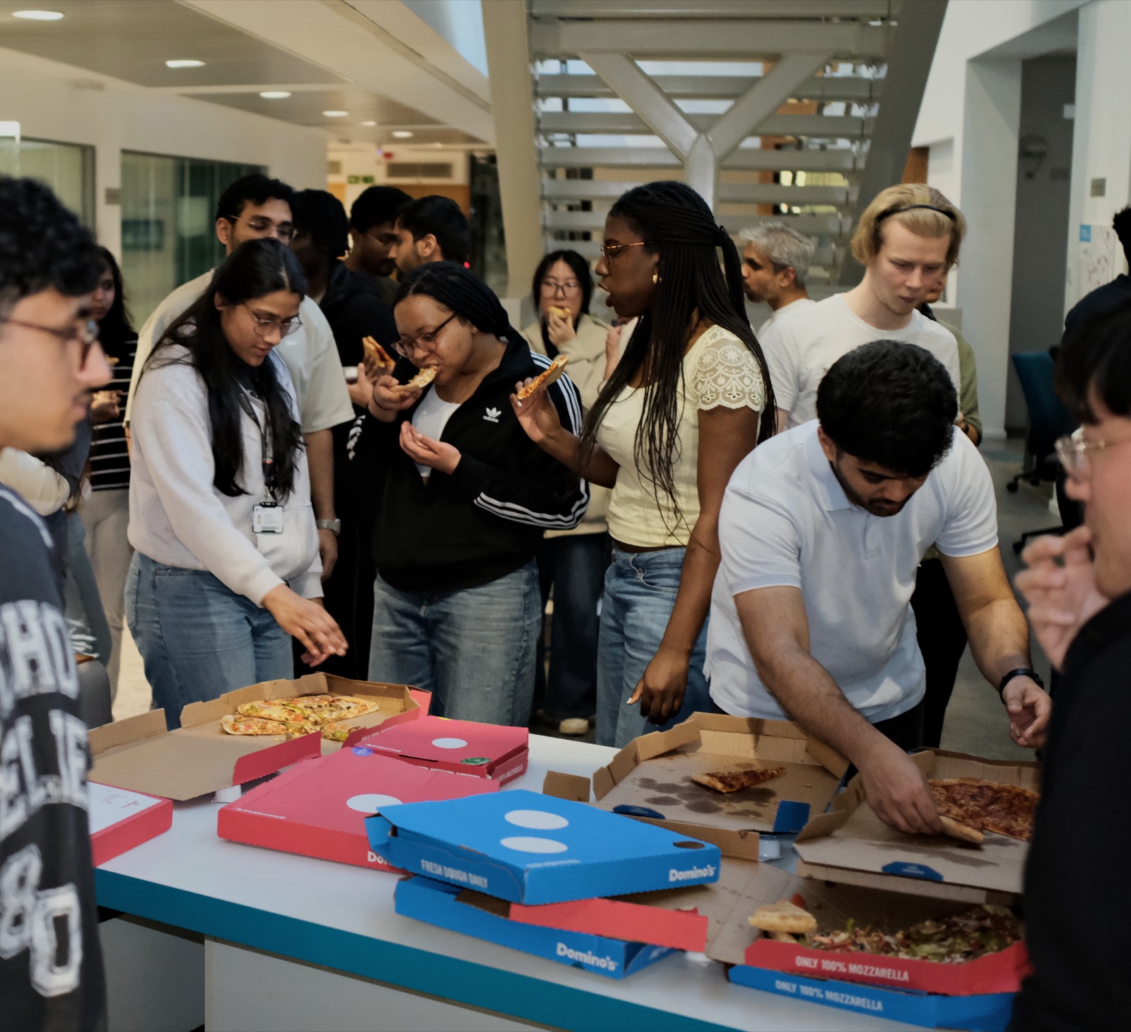 Members gathered around a table of pizza boxes between build sessions