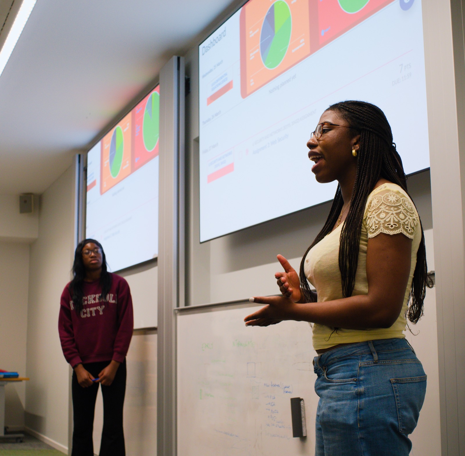 A member pitching their team's prototype in front of a projected screen